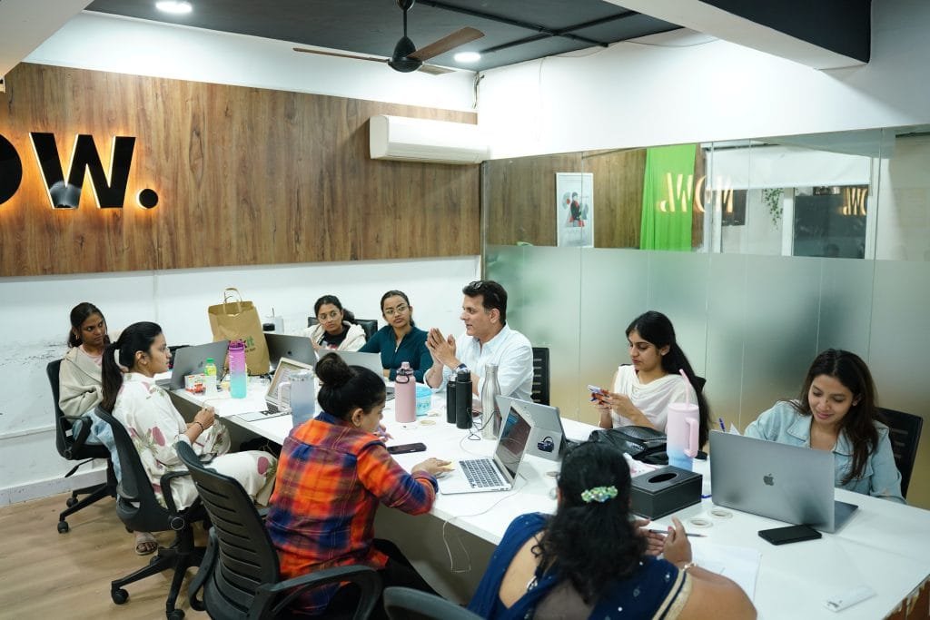 Team meeting at Digital Mojo Hyderabad office with professionals collaborating around table with laptops