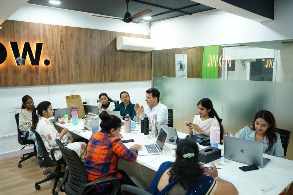 Digital marketing team collaborating in modern office meeting room with laptops and notebooks