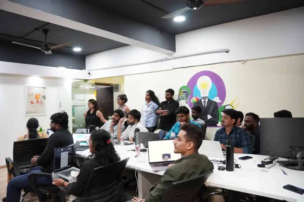 Digital marketing team collaborating in modern office meeting room with laptops and creative wall graphics