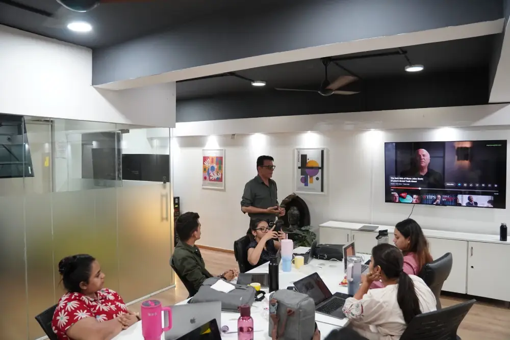 Digital marketing team collaborating in modern office meeting room with video conference display