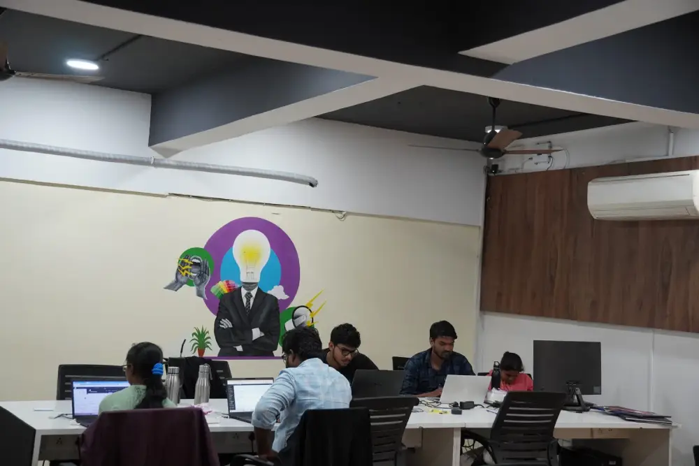 Digital marketing team collaborating at desks in modern office with creative wall art and laptops
