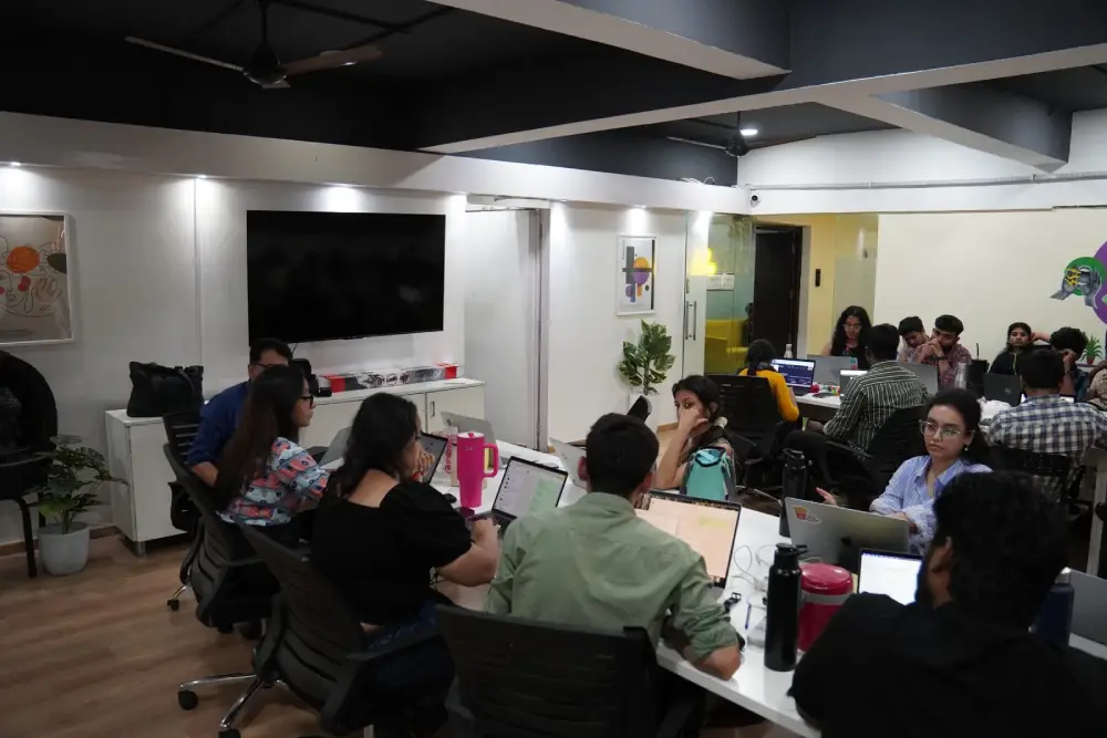 Professional team meeting at Digital Mojo Hyderabad office with employees collaborating around desks with laptops