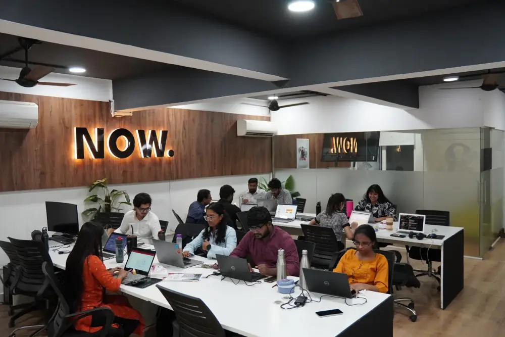 Digital Mojo team collaborating in modern office workspace with laptops and collaborative setup