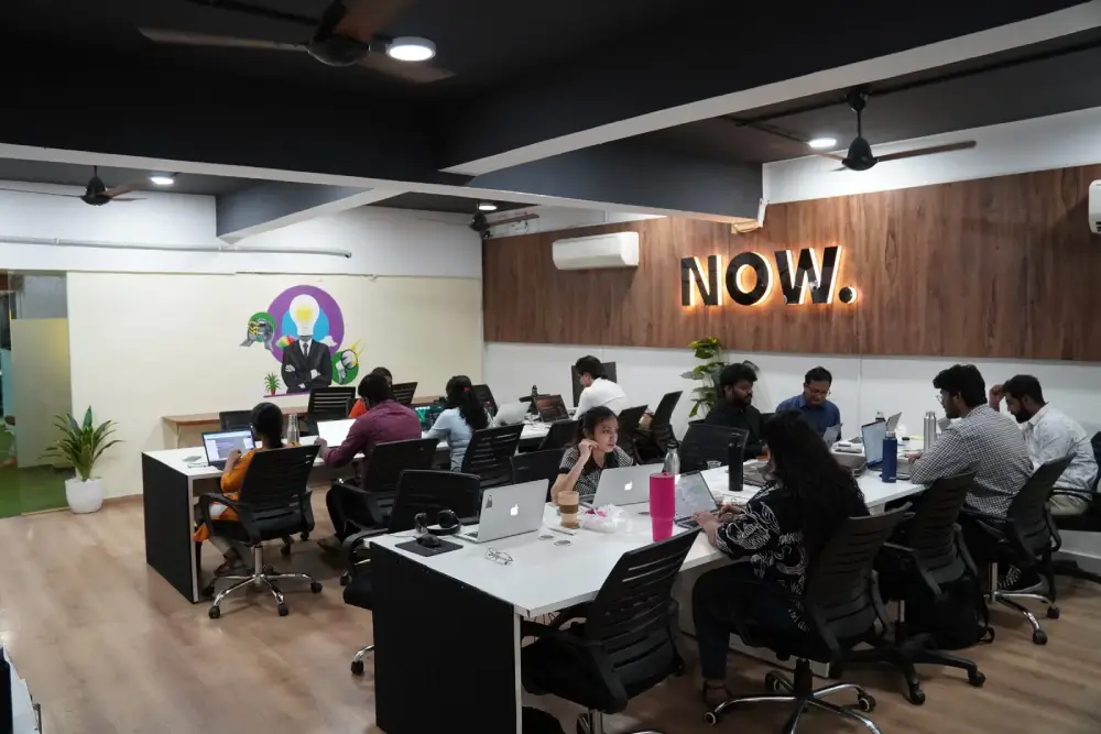 Modern coworking space with professionals working at desks with laptops in a creative office environment