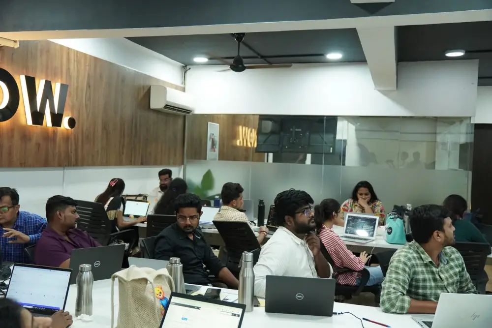 Professional team collaborating in modern office workspace with laptops and workstations