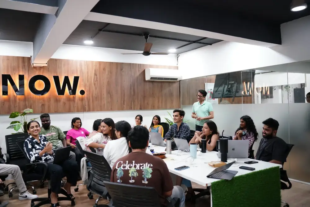 Digital Mojo team meeting in Hyderabad office with diverse professionals collaborating around table with laptops