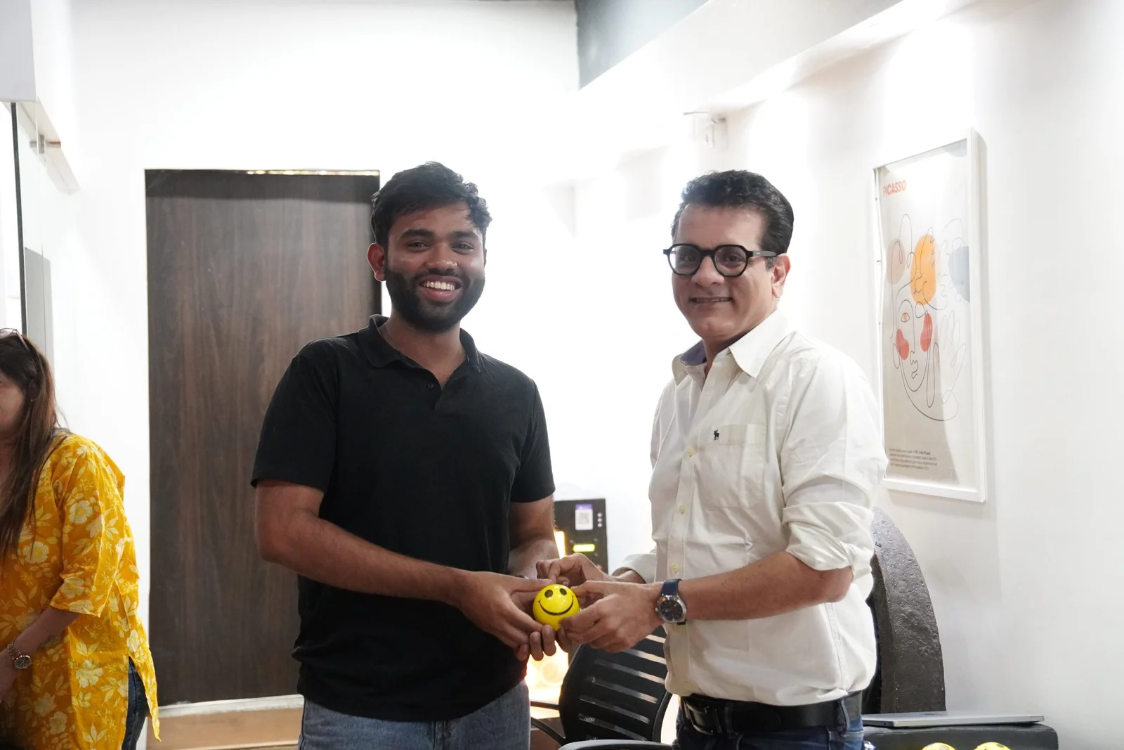 Two professionals shaking hands at Digital Mojo office in Hyderabad, India, exchanging a yellow smiley face stress ball