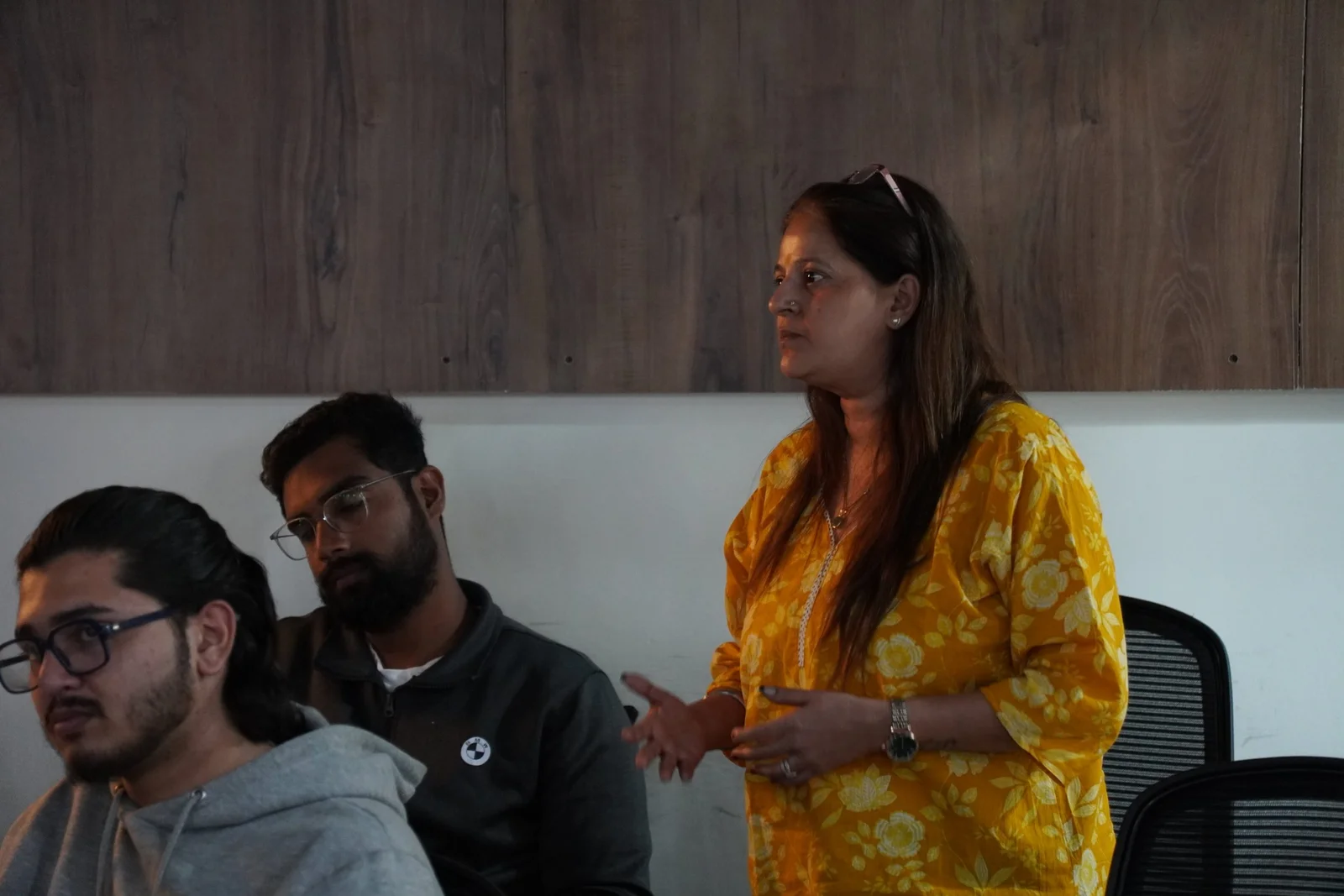 Female professional in yellow traditional outfit presenting to team members in modern office meeting room