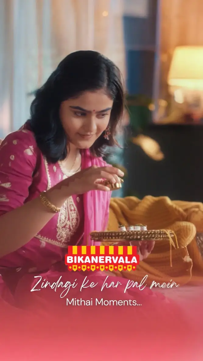 Woman in pink traditional Indian outfit decorating with lights for Mithai moments celebration