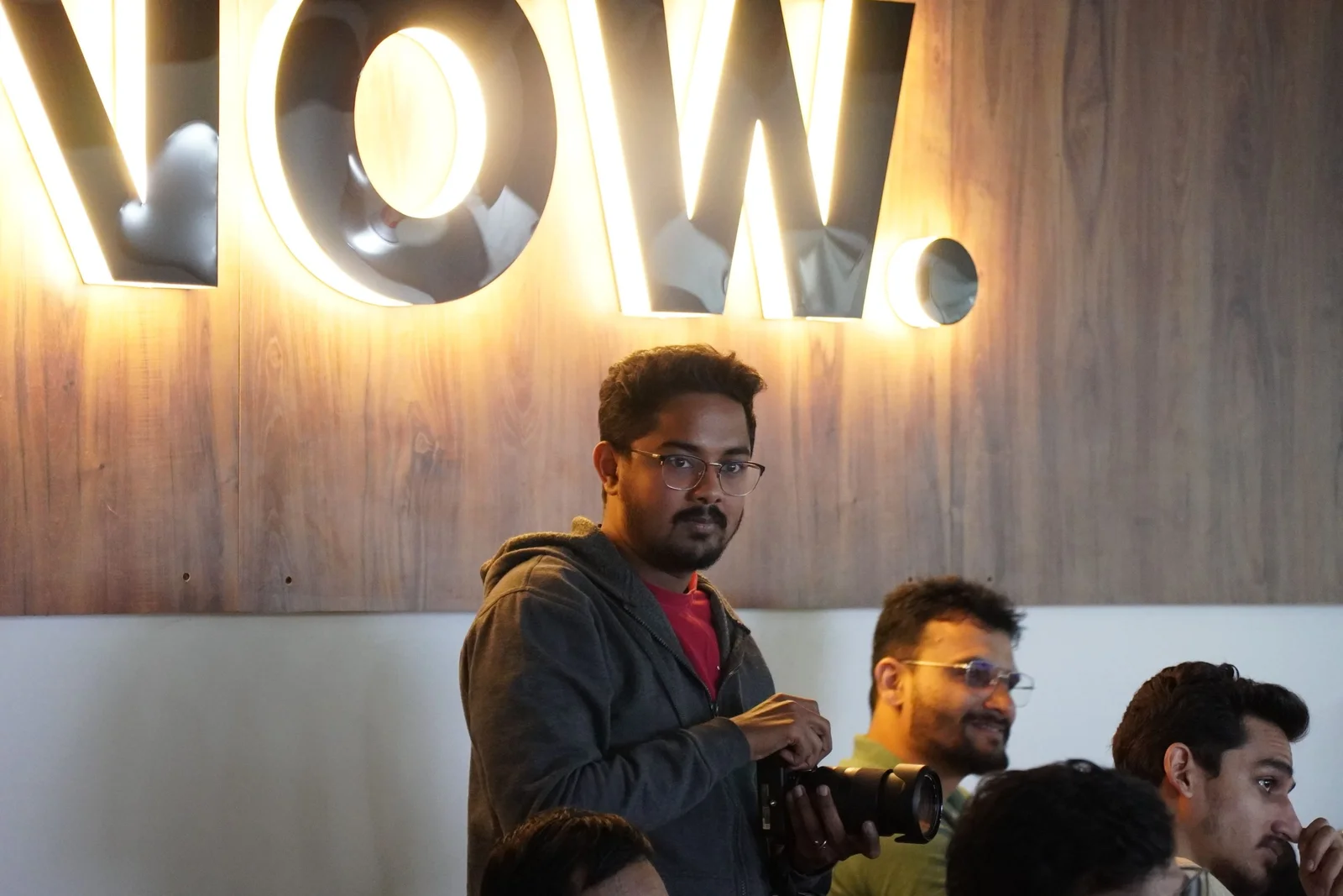 Digital Mojo team members at Hyderabad office event with neon signage, showcasing creative professionals